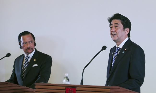 Brunei Sultan Hassanal Bolkiah (left), chairman of ASEAN, listens as Japanese Prime Minister Shinzo Abe speaks during a joint press announcement at Akasaka Palace state guesthouse in Tokyo on Saturday.   AP-Yonhap News