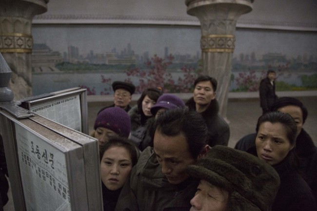 North Korean commuters gather around a public newspaper on a subway platform in Pyongyang to read the headlines about Jang Song-thaek on Friday.   AP-Yonhap News