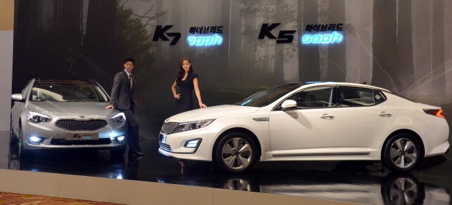 Kia Motors unveils hybrid versions of its flagship K5 (right) and K7 sedans, named 500h and 700h, at a launch event at a hotel in Seoul on Monday.   Kim Myung-sub/The Korea Herald