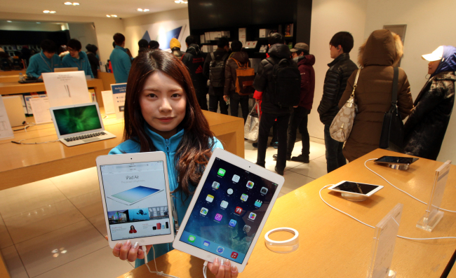 An Apple store employee holds the newly launched iPad Air and Retina iPad mini. (Yonhap News)