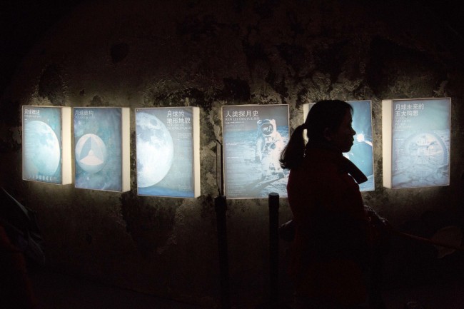 A woman walks past posters during a moon exhibit at the China Science and Technology Museum in Beijing on Sunday.   AP-Yonhap News