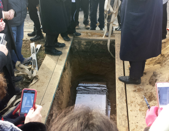 This photo provided by a participant at a special service at New Montefiore Cemetery in West Babylon, New York, shows damaged Torah scroll fragments being buried in a religious ceremony at the cemetery on Sunday.    AP-Yonhap News