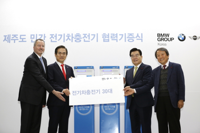 BMW Group vice president William McAndrews (from left), BMW Korea CEO Kim Hyo-joon, Jeju Gov. Woo Keun-min and Jeju Electric Vehicle Service president Kim Dae-hwan pose after the German carmaker donated 30 charging poles for electric vehicles to Jejudo Island on Tuesday. BMW will debut its first full-electric i3 in Korea in May.   BMW Korea