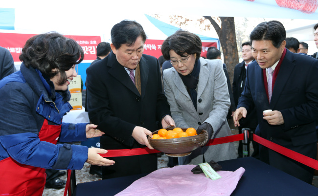 Saenuri Party floor leader Choi Kyung-hwan (second from left) and Supreme Council member Lee Hye-hoon (second from right) admire a porcelain bowl donated by President Park Geun-hye at the party’s charity bazaar in Seoul on Wednesday.   Yonhap News