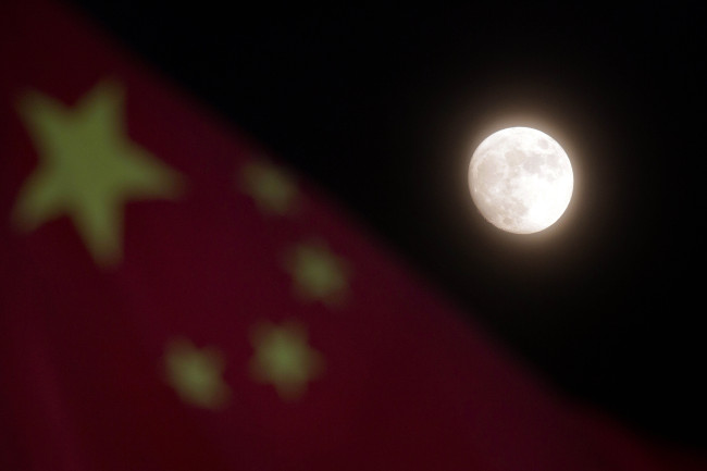 The moon hangs over the Chinese national flag in Beijing.   AP-Yonhap News