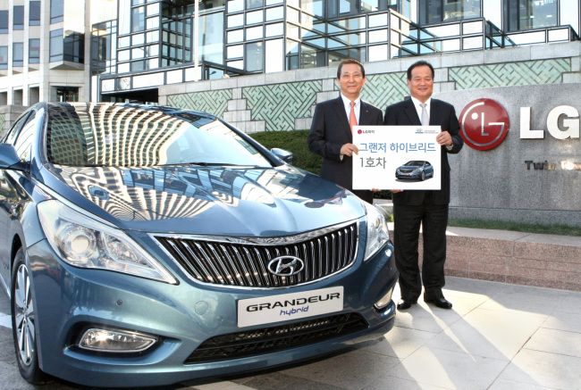 Hyundai Motor president Kim Choong-ho (right) and LG Chem president Kwon Young-soo pose after the carmaker delivered the very first Hybrid Grandeur to the battery supplier at the LG headquarters in Yeouido, Seoul, Wednesday. As part of their environmentally friendly partnership, LG Chem will use the hybrid sedans for its executives.   Hyundai Motor