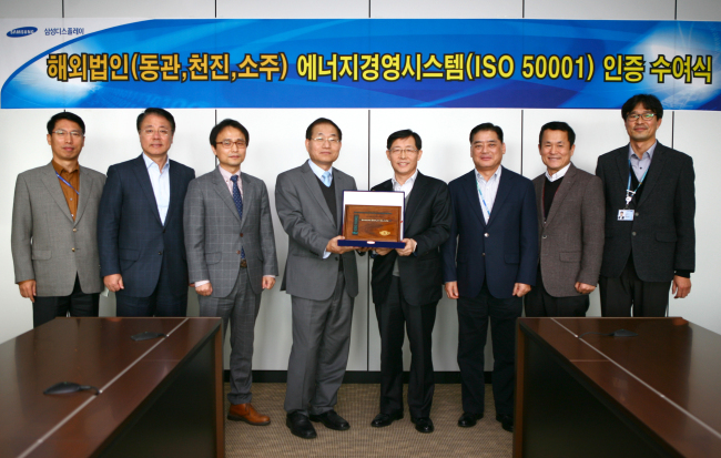 Samsung Display executive vice president Lee Sun-yong (fourth from right) poses with DQS UL Korea managing director Lee Jang-sook (fifth from right) after receiving a declaration of conformance at a ceremony in Asan on Wednesday. The company was certified with the “ISO 50001” ― a standard for superior energy management systems set by the International Organization for Standardization ― at three of its overseas locations in China.   Samsung Display