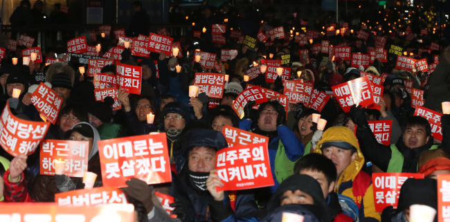 Hundreds of activists stage a candlelight vigil in central Seoul on Saturday, protesting the government’s crackdown on a railway workers’ strike and calling for an independent investigation into government agencies alleged to have interfered in last year’s presidential election.   Yonhap News