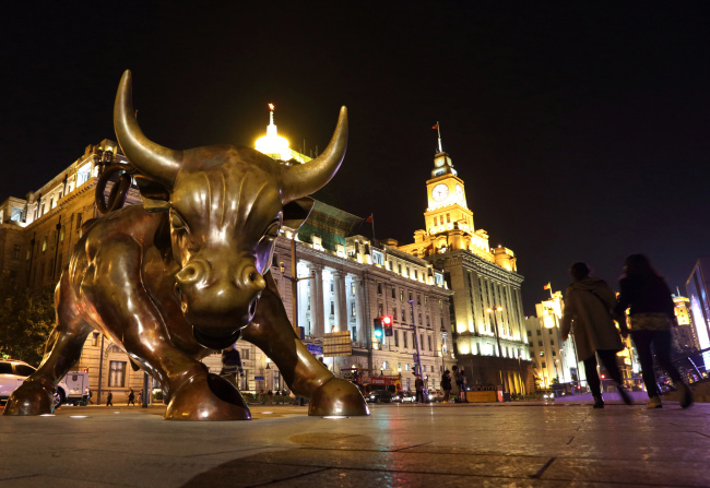 Pedestrians walk past Arturo Di Modica’s “The Bund Financial Bull” sculpture on the Bund in Shanghai.   Bloomberg