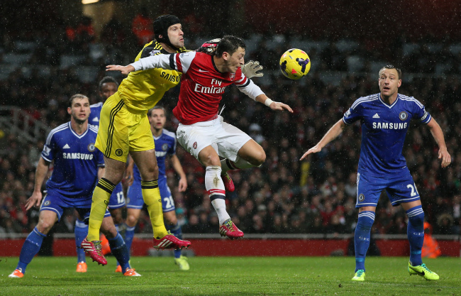 Chelsea goalkeeper Petr Cech punches the ball clear while under pressure from Arsenal’s Mesut Ozil on Monday.   AP-Yonhap News