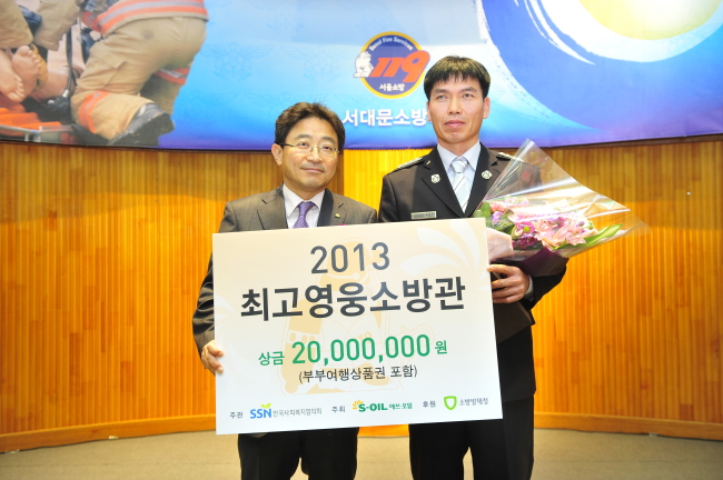 S-Oil senior vice president Lee Chang-jai (left) poses with the winner of the “hero firefighter” of 2014 award Moon Gwon-ju from Gwangsan Fire Station in Gwangju after handing over a plaque of appreciation and a prize of 20 million won ($19.000). Moon rescued six people buried under a collapsed new building in the city in June.   S-Oil