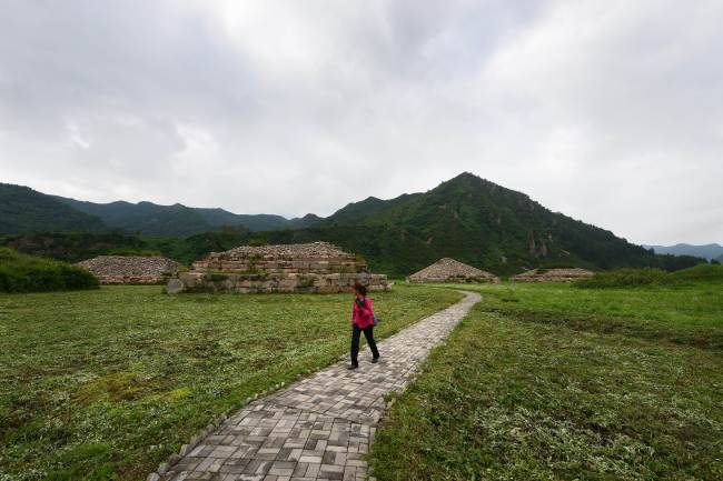 A woman walks past tombs at a heritage park in the Chinese border city of Jian, in northeast China’s Jilin Province.    AFP-Yonhap News