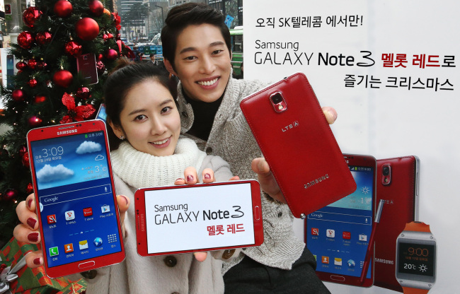 Models pose with the Galaxy Note 3 in merlot red, which was released last week, at a Christmas event in Seoul on Tuesday.   Samsung Electronics
