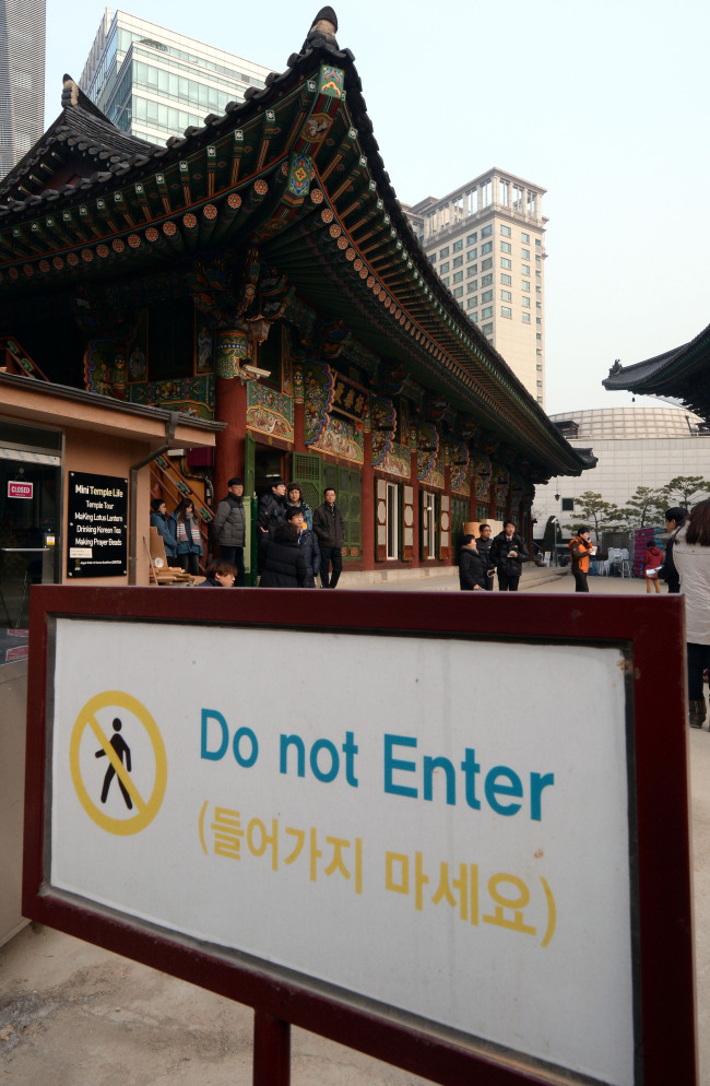 People loiter around Jogyesa Temple’s main hall as railway unionists continued to take refuge in the Seoul temple for the third day on Thursday.   Ahn Hoon/The Korea Herald