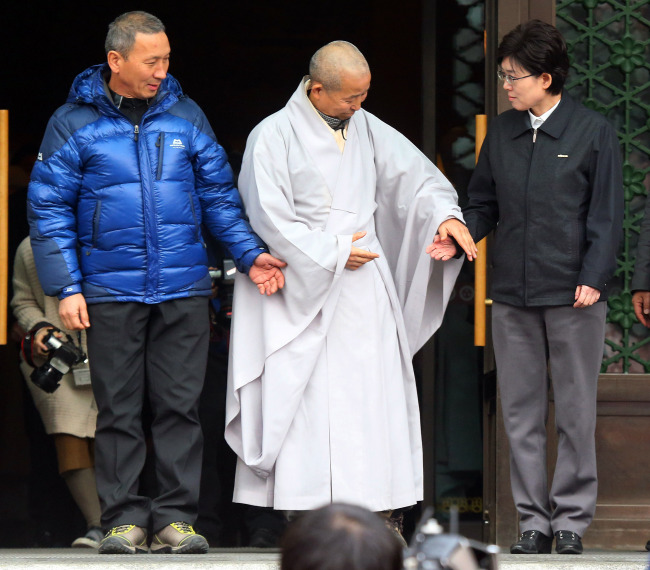 KORAIL CEO Choi Yeon-hye (right) and rail union deputy leader Park Tae-man (left) stand awkwardly as Jogyesa Temple Ven. Dobeob asks them to shake hands before holding a three-way meeting to resolve the railway strike at a Buddhist cultural hall in Seoul on Thursday.   Park Hae-mook/The Korea Herald