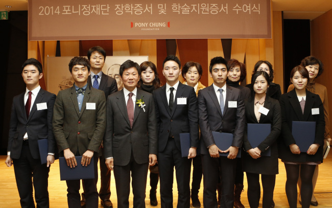 Chung Mong-gyu (third from left, front row), chairman of the Pony Chung Foundation, poses with scholarship recipients and their parents in ceremony in Seoul on Friday.   Hyundai Development Co.