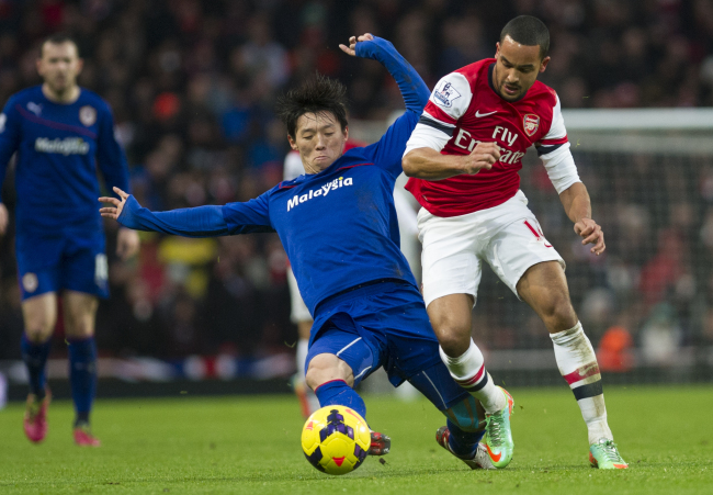Arsenal’s Theo Walcott (right) fights for the ball with Cardiff City’s Kim Bo-kyung at Emirates Stadium in London on Wednesday.   AP-Yonhap News