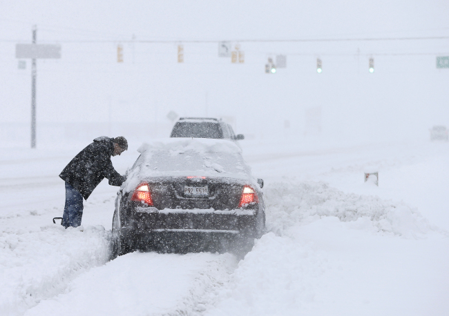 A motorist helps dig out a driver stuck in a snow drift in Zionsville, Indiana, Sunday.   Yonhap News