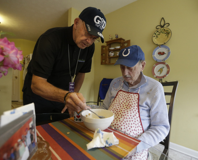 Caregiver Warren Manchess (left) helps Paul Gregoline with a meal in Noblesville, Indiana, on Nov. 21.   AP-Yonhap News