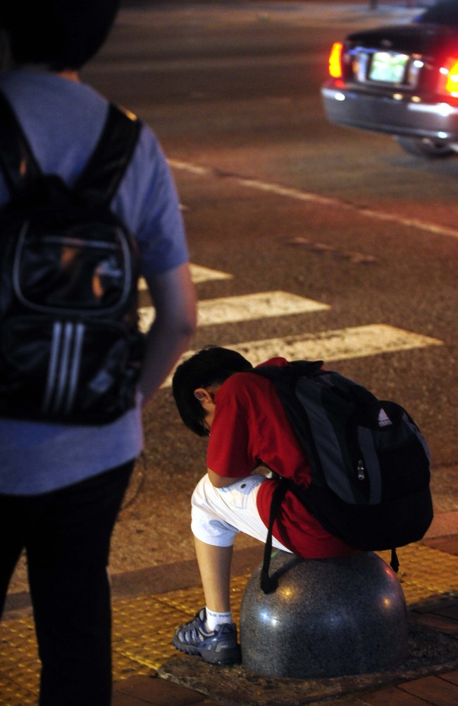 A young boy sits on the road near a complex packed with private institutions in Daechi-dong, Seoul.   File Photo
