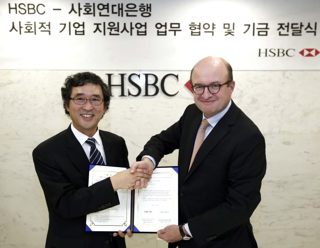 HSBC Korea president and CEO Martin Tricaud (right) poses with Social Solidarity Bank CEO Kim Yong-deog after donating 100 million won ($91,000) as part of its participation in philanthropic activities at the British financial firm’s Seoul unit, Wednesday.   HSBC Korea