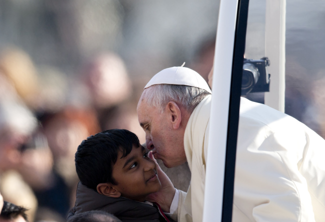 Pope Francis kisses a child as he arrives for his weekly general audience in St. Peter’s Square at the Vatican on Wednesday.   AP-Yonhap News