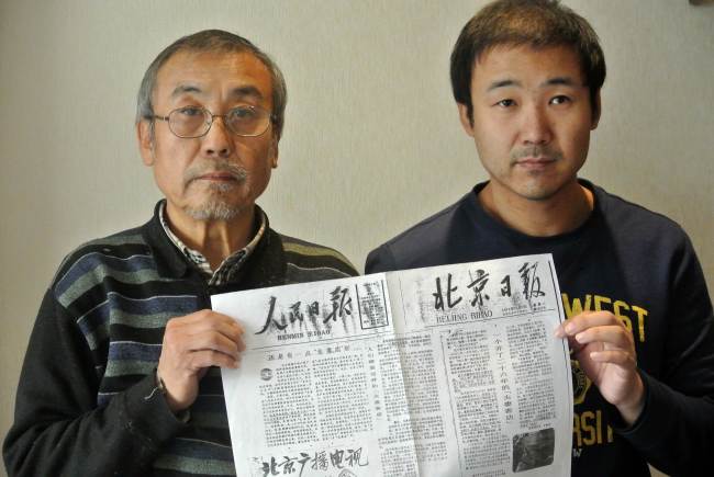Qiao Shuzhi (left) and his son Qiao Xuan hold a copy of the People’s Daily and Beijing Daily front page from 1979, each with an editorial about Tianyi Inn, Jan. 7.   AFP-Yonhap News