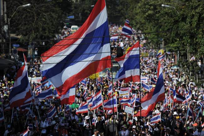 Antigovernment protesters wave national flags as they march through the streets of Bangkok in a move to shut down the city on Monday.   AFP-Yonhap News