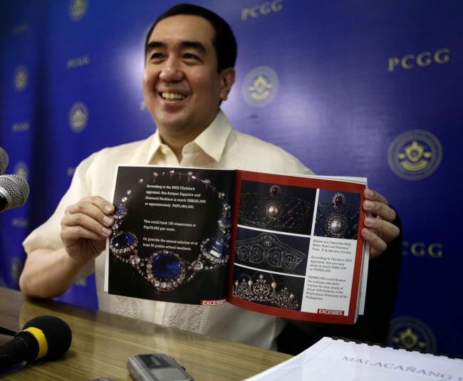 Andres Bautista, chairman of the Presidential Commission on Good Government, shows a catalog of a seized jewelry collection belonging to the Marcoses at a news conference in Mandaluyong city, northeast of Manila, Tuesday.   AP-Yonhap News