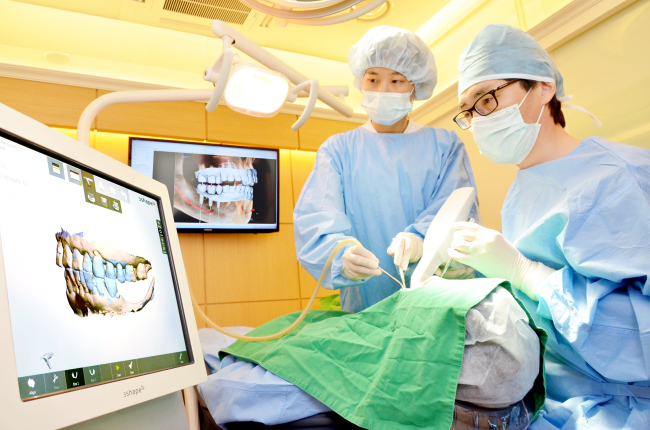 Dr. Lee Jeong-tack (right) performs implant surgery at S-Plant Dental Hospital in Seoul.   S-Plant Dental Hospital