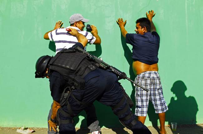 Mexican federal police check men in the streets of Apatzingan, Michoacan state, Mexico, Wednesday.   AFP-Yonhap News