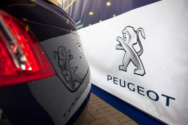 The Peugeot logo is seen reflected on the trunk of a Peugeot 508 automobile in Berlin.   Bloomberg