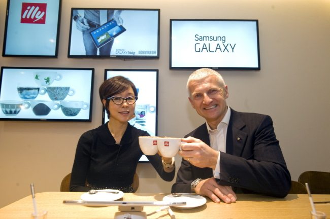 Lee Young-hee (left), vice executive president of Samsung Electronics, poses with Andrea Illy, CEO of illycaffe, at an Illy cafe in London on Monday. The two companies have signed a partnership with Samsung providing its smart devices to Illy’s flagship coffee houses, while Illy coffee will be provided in Samsung’s showrooms worldwide. Samsung Electronics