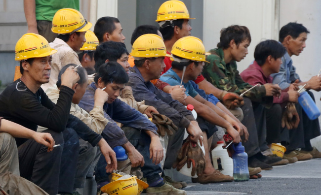 Workers take a break outside a construction site in Shanghai.    Bloomberg