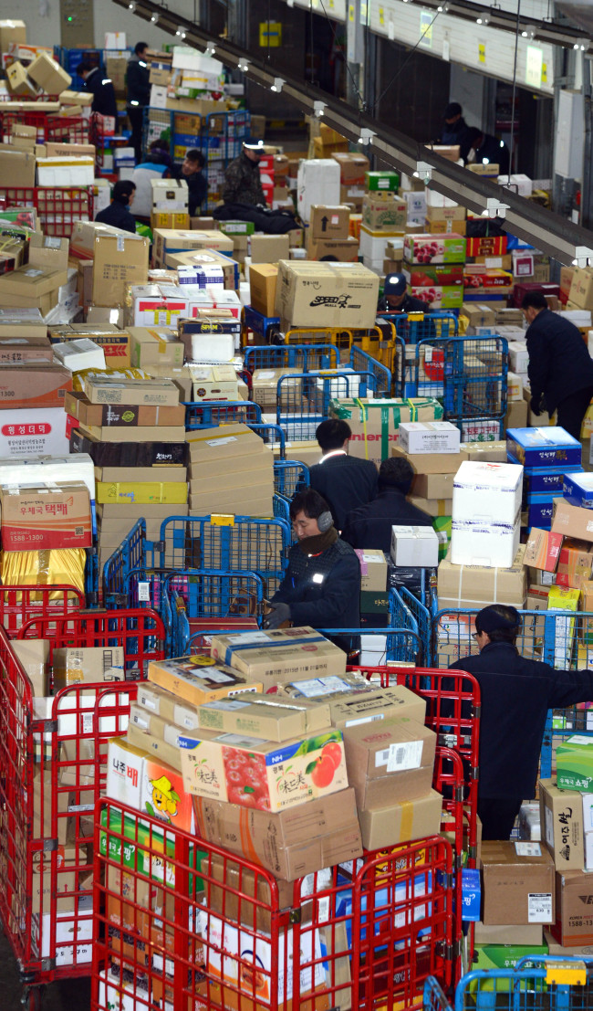 Employees at a Seoul post office process parcels Tuesday, ahead of Lunar New Year’s Day.   Kim Myung-sub/The Korea Herald