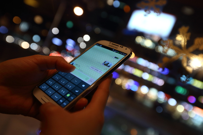 A woman uses the Kakao Corp. messaging app KakaoTalk on a Samsung Electronics Galaxy S4 smartphone in this arranged photograph taken in Seoul.   Bloomberg