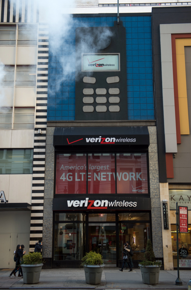 Pedestrians walk past a Verizon Wireless store in New York.   Bloomberg