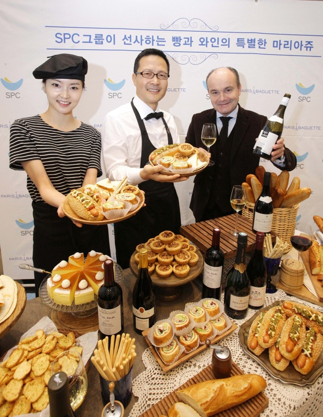 Jung Tae-soo (center), head of Paris Croissant operated by SPC Group, poses Wednesday with French sommelier world champion Olivier Poussier, who was invited to Paris Croissant’s Gwanghwanmun outlet to help customers choose the wine that is most compatible with SPC pastries and desserts.   SPC Group