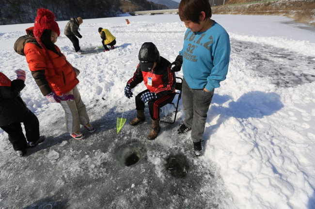 Visitors fish through a hole cut into a frozen reservoir at the Anseong Ice Fishing Festival last year.
(Anseong Ice Fishing Festival)