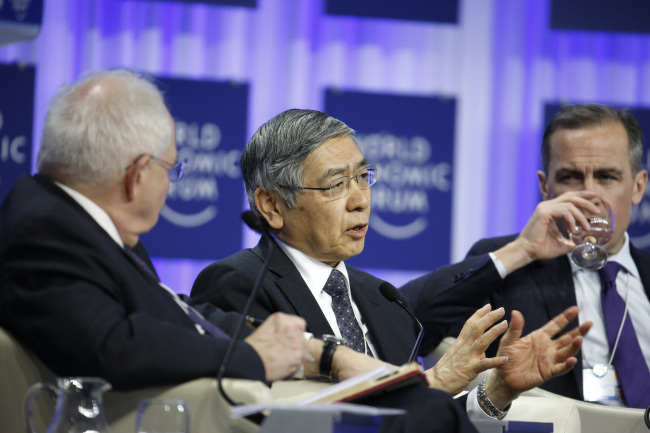 Haruhiko Kuroda (center), governor of the Bank of Japan, speaks as Mark Carney (right), governor of the Bank of England, listens during a panel session on day four of the World Economic Forum in Davos, Switzerland, Saturday.   Bloomberg
