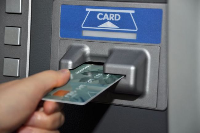 User withdraws cash from automated teller machine, using a credit card. (123RF)