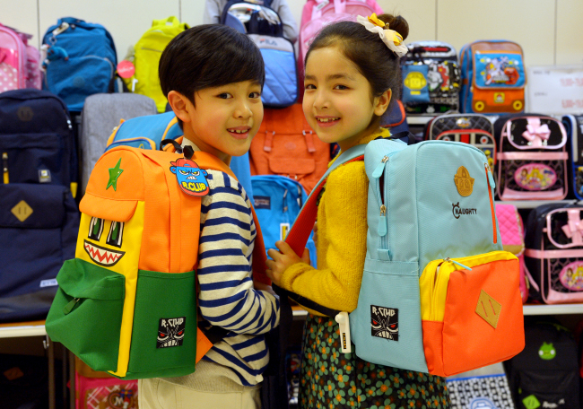 Children model school bags at Emart, where backpacks, indoor slippers and other school-related supplies are on sale to mark the start of a new school year in March.   Yoon Byung-chan/The Korea Herald