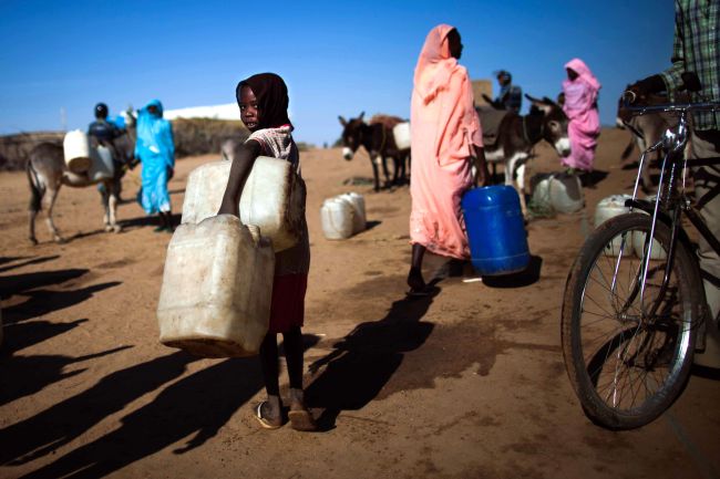 A child carries two jerry cans at a water point in Al-Shaddad Camp for Internally Displaced Persons in North Darfur.   AFP-Yonhap
