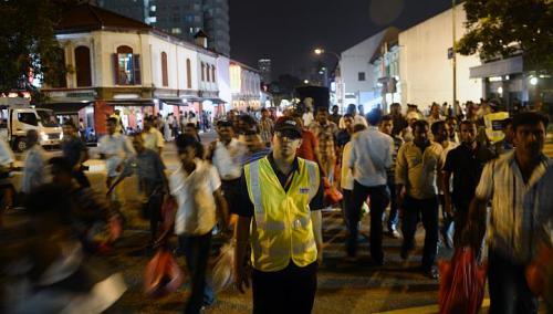 An auxiliary police officer helps to direct pedestrians in front of the busy junction at Kerbau Road in Little India on Sunday. The authorities are expected to continue to keep a close watch on the area. The stepped up patrols by auxiliary police officers are one sign of that.   The Straits Times