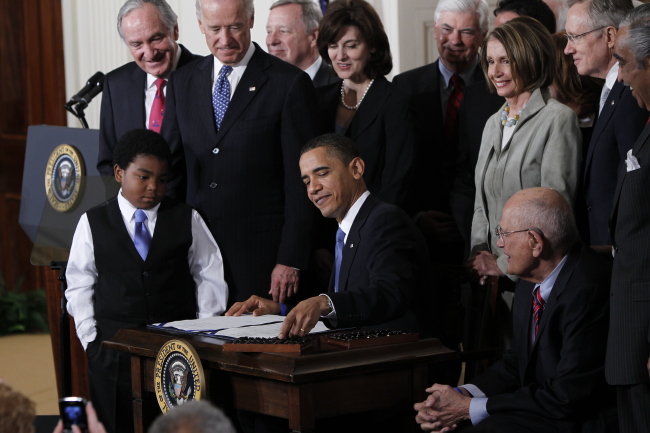 President Barack Obama reaches for a pen to sign the health care bill in the East Room of the White House in Washington on March 23, 2010.   AP-Yonhap