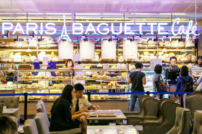 People sit and eat at the fourth Paris Baguette store to open in Singapore at the country’s Changi Airport. Parent company SPC Group said it has become the first Korean bakery brand to run an outlet in an international airport outside Korea.   SPC Group