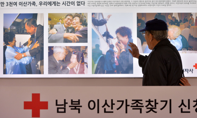 Han Dong-gyo, 87, a South Korean citizen who left behind his hometown in Hwanghae Province, North Korea, touches the pictures of past separated family reunions in front of the Red Cross office in Seoul on Thursday. There have been 18 reunions since 2000 between the two Koreas, allowing 1,874 South Koreans to see their families in the North for perhaps the last time. Han is one of the 120,000 South Koreans who have yet to see their separated kin since the end of the Korean War in 1953. It is uncertain whether the two Koreas will hold family reunions later this month as agreed to on Wednesday.   Lee Sang-sub/The Korea Herald