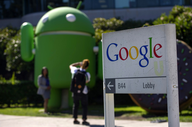 Pedestrians take pictures in front of a Google Inc. office building at the company’s headquarters in Mountain View, California.   Bloomberg
