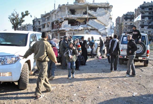 Civilians wait to be evacuated from the besieged district of the Syrian city of Homs by United Nations staff to a safer location Sunday.   AFP-Yonhap