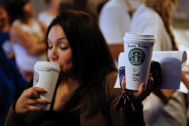 A customer takes a sip of coffee while holding up a cup during a television interview at the Dumb Starbucks Coffee store in Los Angeles.   Bloomberg